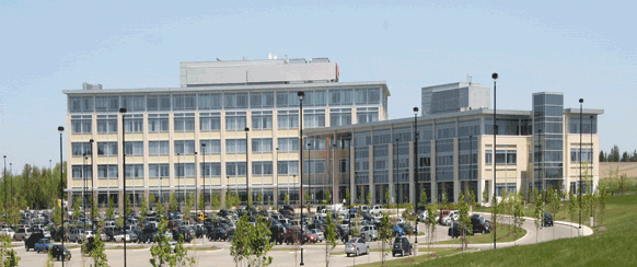 A large parking lot full of cars in front of two buildings